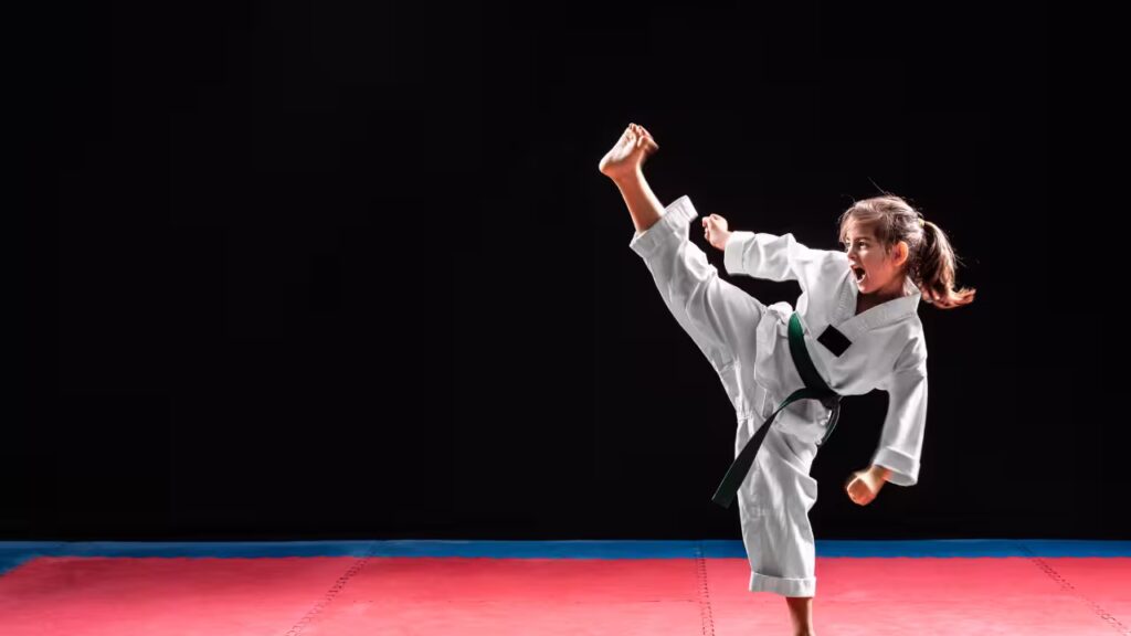 Children practicing martial arts outdoors in a park setting, performing exercises like sparring, kata, and weapon training.