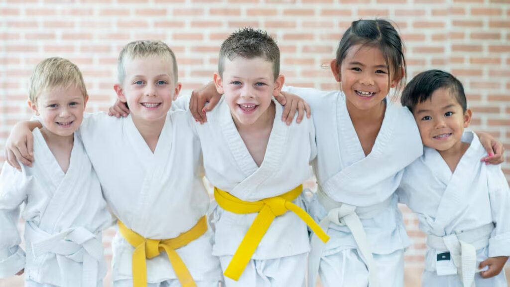 Young children practicing martial arts in a dojo, performing kicks, punches, and blocks under the guidance of an instructor.